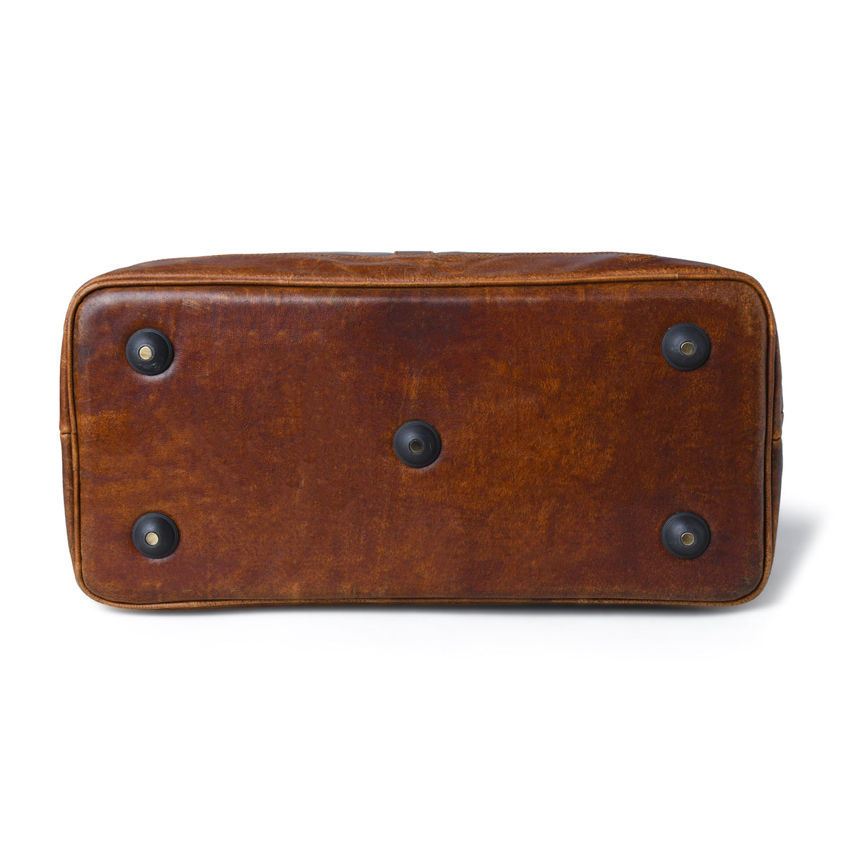 tan brown bottom view of a brown leather bag or case, showing a warm cognac-brown finish with dark metal corner protectors and a central round stud on the base, set against a plain white background.