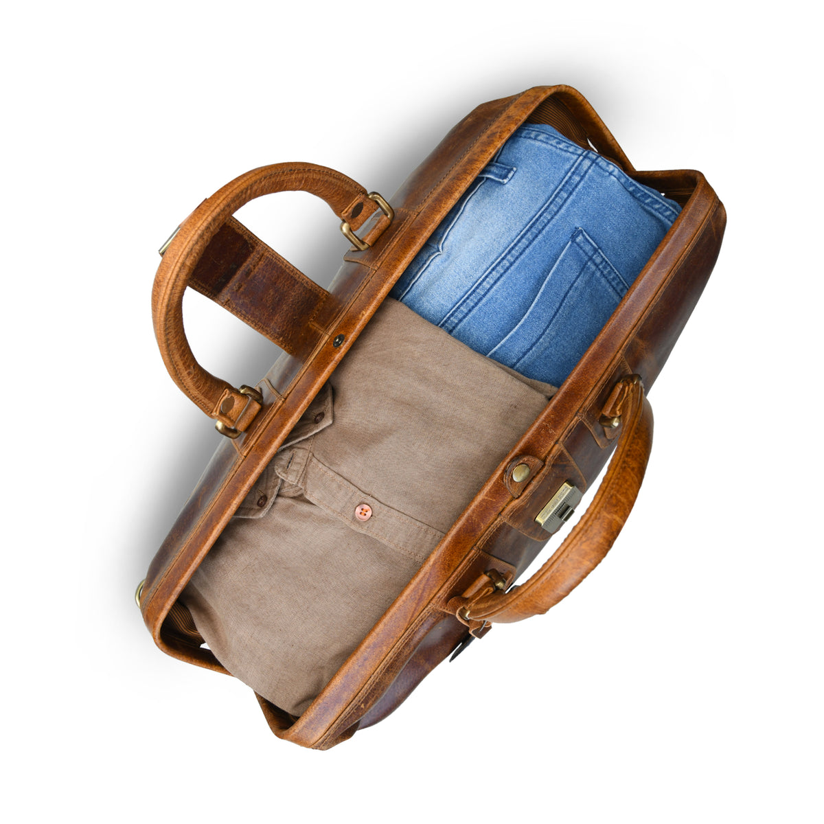 tan brown  leather duffel bag shown from above, partially filled with blue jeans, on a clean white background.