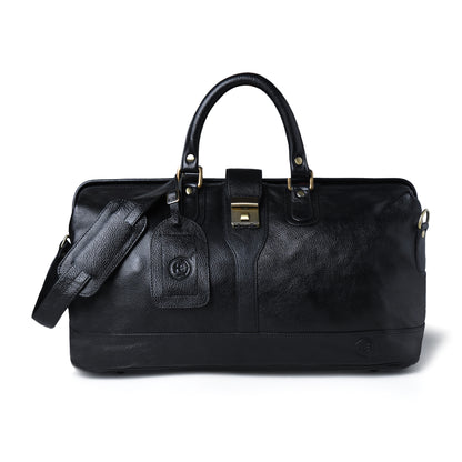 A black leather duffel bag with dual top handles, a detachable shoulder strap, a hanging luggage tag, and gold-tone hardware, photographed on a clean white background.