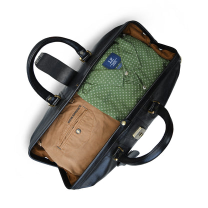A black leather duffel bag shown open from above, containing a green polka-dot button-up shirt and a tan pleated pocket square, on a white background.