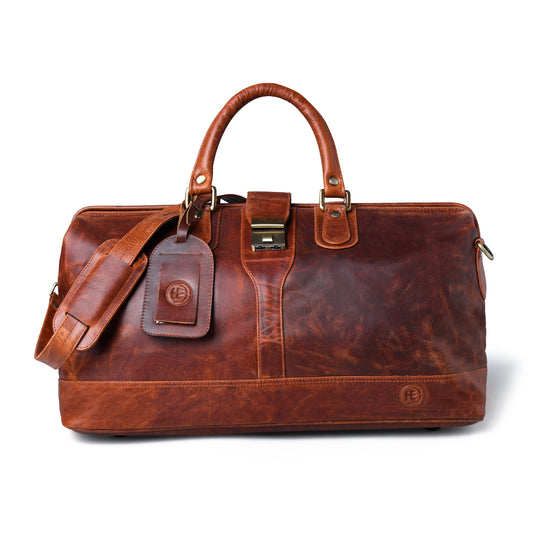 Dark brown distressed leather duffel bag with dual top handles, a detachable shoulder strap, a leather luggage tag, and brass-tone hardware, shown on a white background.