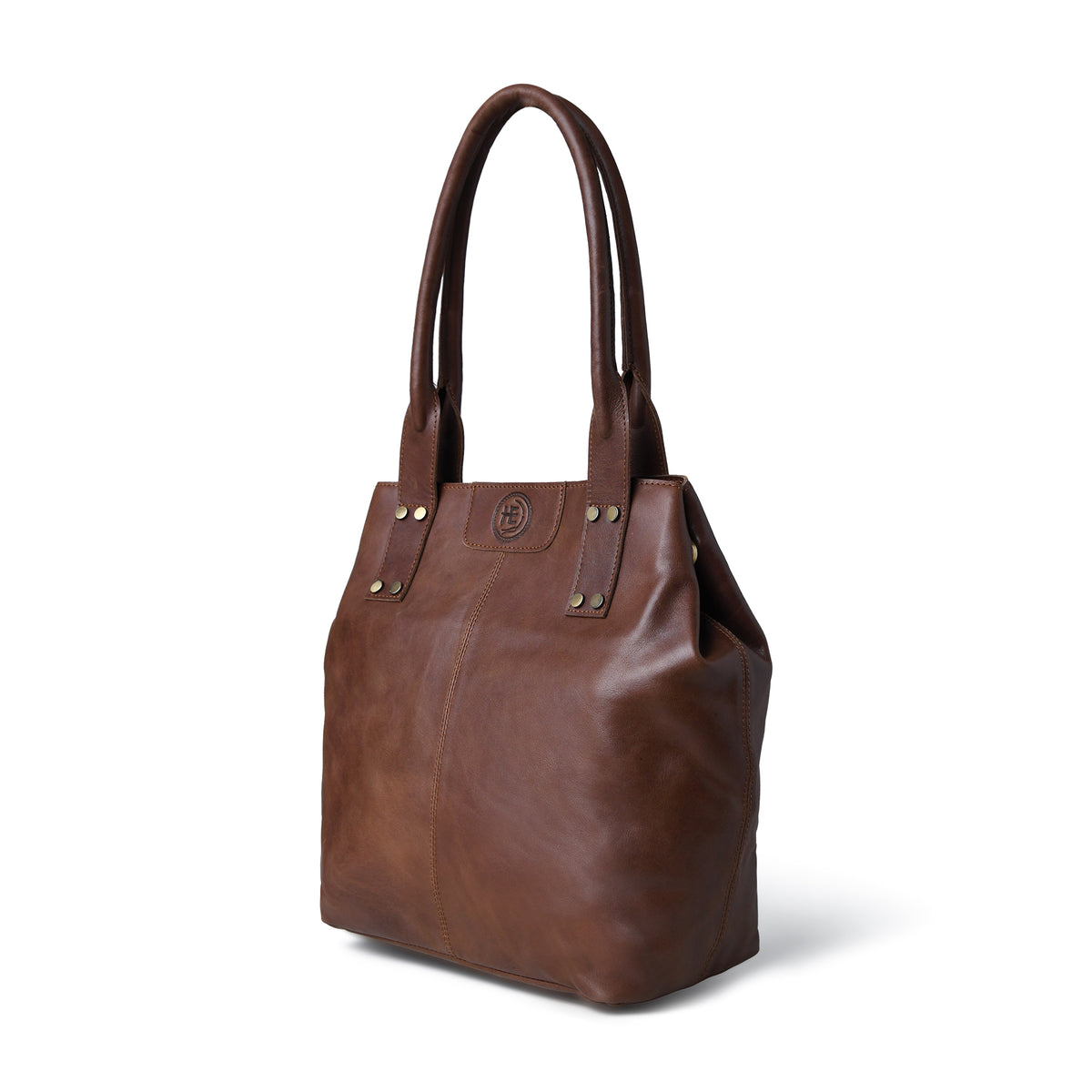 A Dark brown leather tote bag with double shoulder straps, gold-tone rivets, and a small circular logo plaque on the front, shown on a white background.