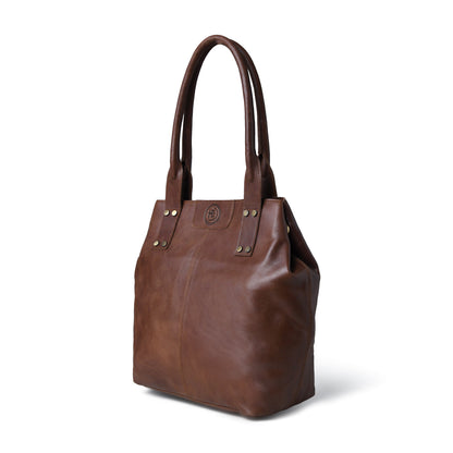 A Dark brown leather tote bag with double shoulder straps, gold-tone rivets, and a small circular logo plaque on the front, shown on a white background.
