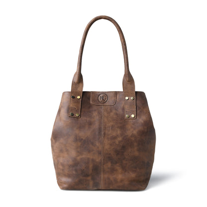 A Tan brown distressed leather tote bag with double shoulder straps, brass-tone rivets, and a circular logo medallion on the front, shown against a plain white background.