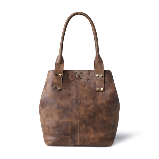 A Tan brown distressed leather tote bag with double shoulder straps, brass-tone rivets, and a circular logo medallion on the front, shown against a plain white background.