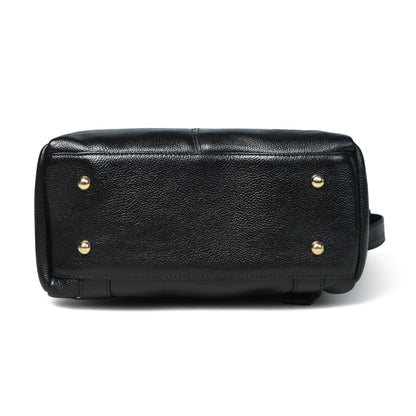 Black pebbled leather handbag bottom view showing metal studs on a white background.