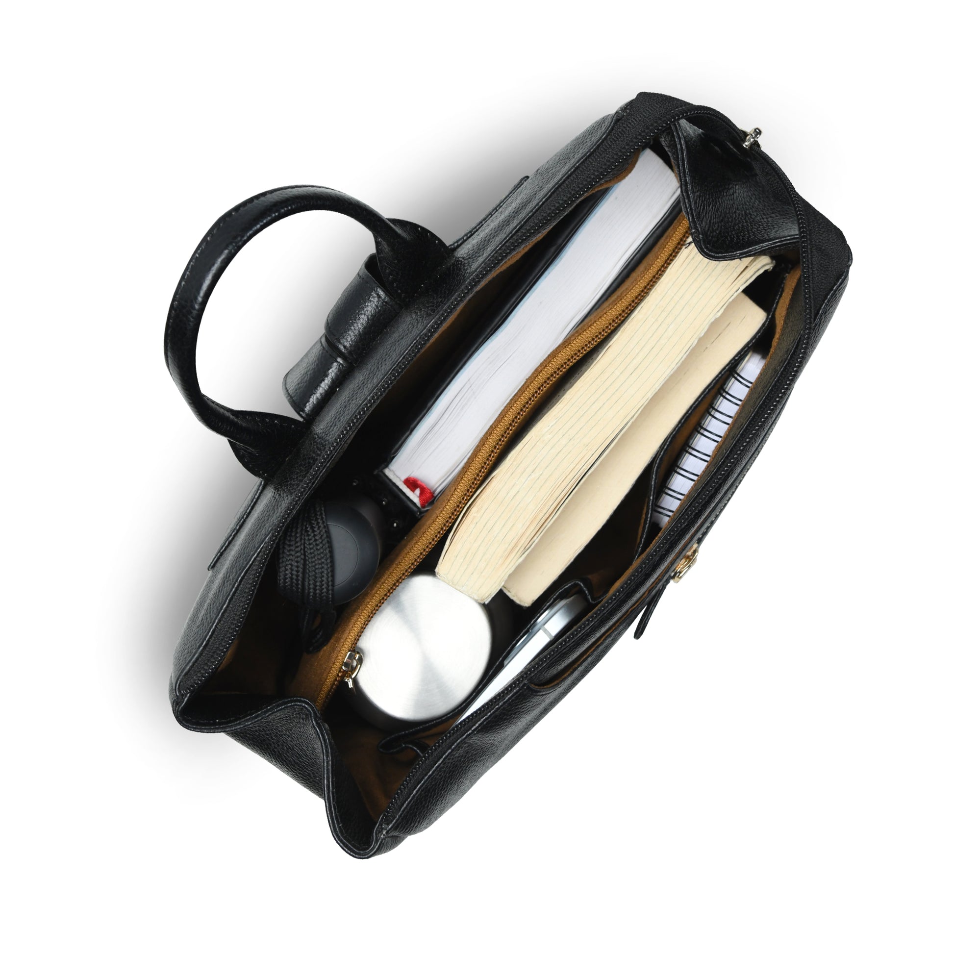 An overhead view of an open black leather bag showing its interior compartments filled with books, a notebook, a pen, and a small round accessory, set against a plain white background.