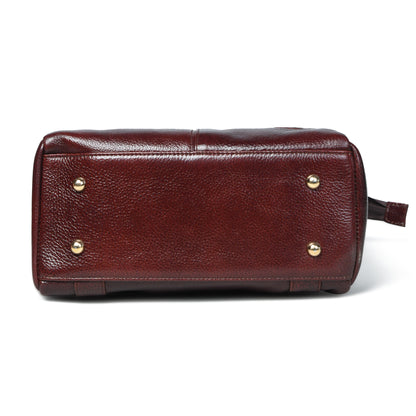 burgundy pebbled leather bag shown from the bottom, featuring four metal studs and a small leather pull tab on the right side, set against a plain white background.