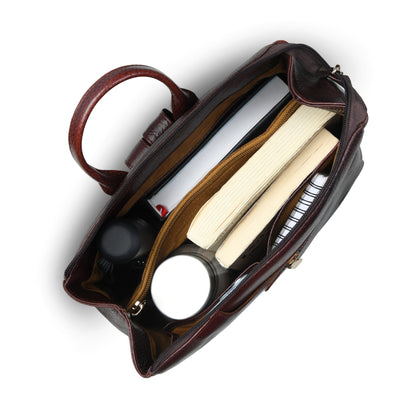 burgundy leather handbag shown from a top-down angle, open to reveal its interior compartments filled with books, a notebook, and small accessories, on a white background.