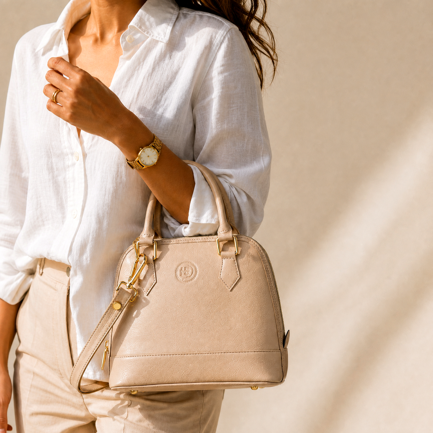 Woman holding a beige handbag with a plain background